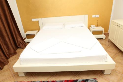 a white bed in a room with two night stands at Hotel Autostrada (Highway) in Kashari