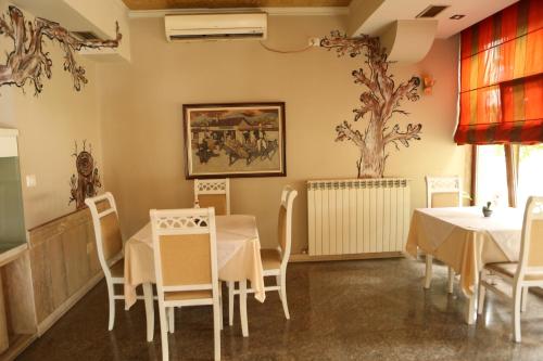 a restaurant with tables and chairs and a tree on the wall at Hotel Autostrada (Highway) in Kashari