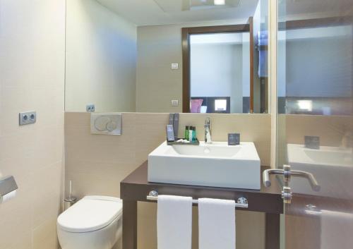 uma casa de banho com um lavatório, um WC e um espelho. em Sercotel Aura Algeciras em Algeciras
