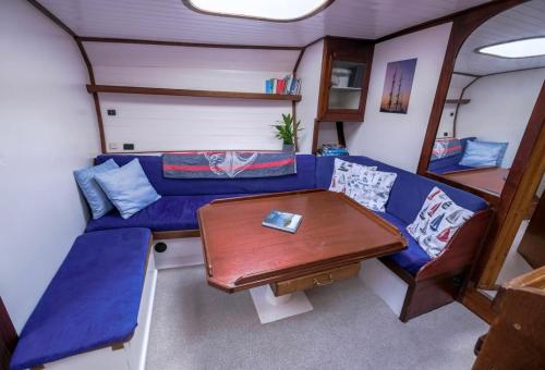 a living room with a blue couch and a table at Stunning Yacht Sea Lion in Charlestown Harbour, Cornwall in Charlestown