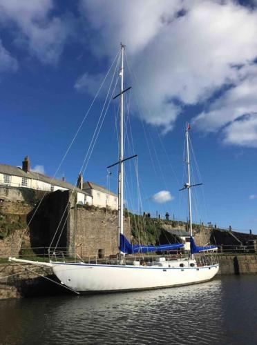 a white sail boat docked next to a brick wall at Stunning Yacht Sea Lion in Charlestown Harbour, Cornwall in Charlestown