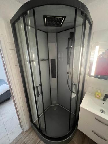 une douche en verre dans une salle de bain avec un lavabo dans l'établissement Appartement en face de la plage avec barbecue, à Plage dʼArgelès