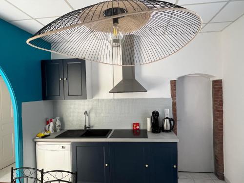 une cuisine avec des armoires bleues et un grand meuble lumineux dans l'établissement Appartement en face de la plage avec barbecue, à Plage dʼArgelès