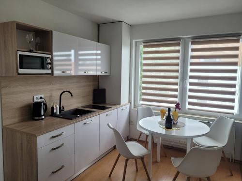 a kitchen with white cabinets and a white table and chairs at Apartman centrum v súkromí Reštaurácia U Jakuba in Martin