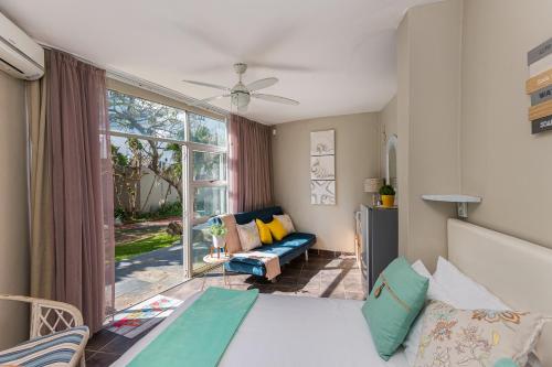 a bedroom with a bed and a couch and a window at Casablanca 6 in Ballito