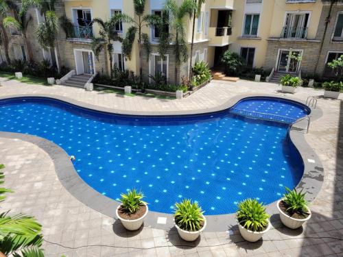 an image of a swimming pool with plants in a courtyard at Kivi's kozy 2bhk luxurious apartment Goa by leela homes in Arpora