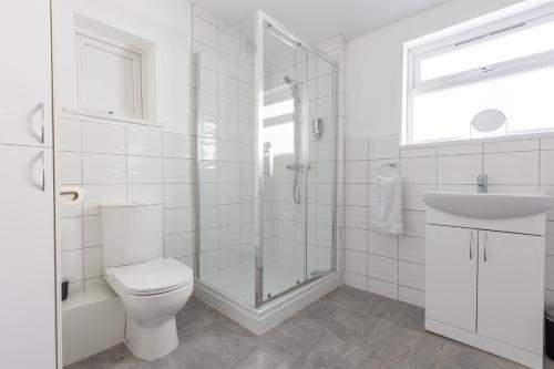 a white bathroom with a toilet and a sink at Platform Stadium apartment with parking in Hull