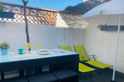 stół z żółtymi krzesłami i parasol na patio w obiekcie La Perle Marine 3 w mieście Le Grau-du-Roi