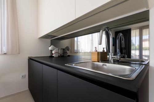 a kitchen with a sink in a black counter top at Villa Piano Residences in Vantačići