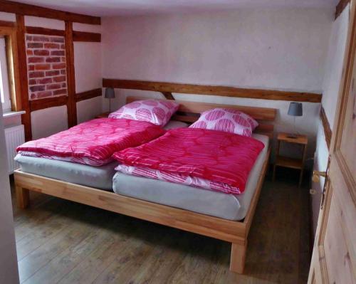 um quarto com 2 camas e lençóis vermelhos em FeWo Dorn OG Haus Sandsteinliebe em Sebnitz