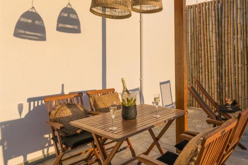 a wooden table and chairs with wine glasses on a patio at Kallia's Suites Milos in Adamas