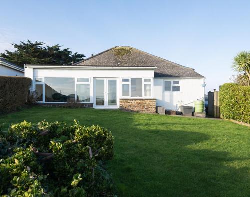 a white house with a yard with green grass at Hillcroft Bungalow in Polzeath