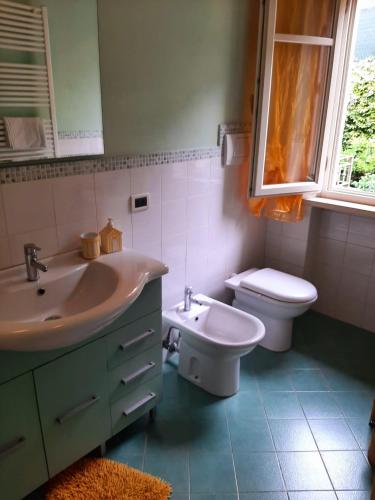 een badkamer met een wastafel, een toilet en een raam bij Casa Marta in Massa