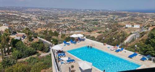 a swimming pool with chairs and a view of a city at Pissouriana hotel Apartments in Pissouri