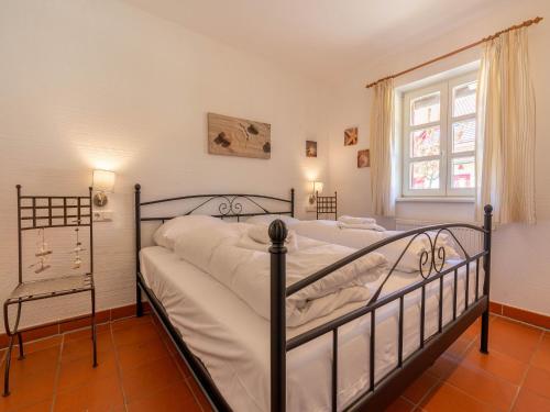 une chambre avec un lit avec des draps blancs et une fenêtre dans l'établissement Feriendorf Rugana - Komfortplus Appartement mit 1 Schlafzimmer und Terrasse B43, à Dranske