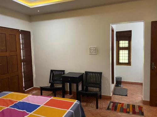- une chambre avec un lit, deux chaises et une table dans l'établissement Maleyam Homestay Riverside, à Kozhikode