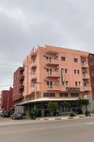 un grande edificio rosa sul lato di una strada di Hotel Achokre a Oulad Yaïch