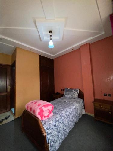 a bedroom with a bed with a pink pillow on it at Hotel Achokre in Oulad Yaïch