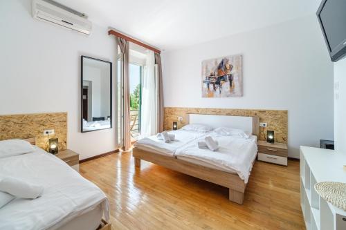 a white bedroom with two beds and a mirror at Stay in Meta Mate in Split