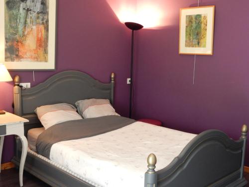 um quarto com uma cama com uma parede roxa em Gîte à la campagne proche d'Angers et de la Loire em Saint-Martin-du-Fouilloux