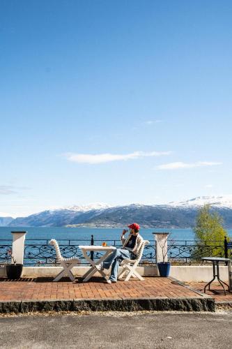a man sitting at a picnic table overlooking the water at Balestrand Hotel in Balestrand