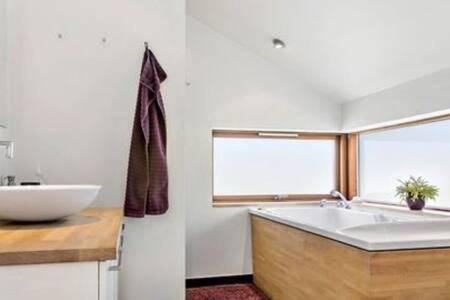 y baño con lavabo y bañera blanca. en Luxury 109m2 cottage DunesNorthSea LøkkenBlokhus Denmark en Løkken