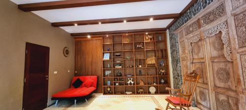 a living room with a red chair and a book shelf at Avalon Ubud Castle & SPA in Ubud