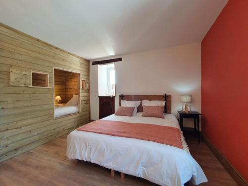 - une chambre avec un lit et un mur rouge dans l'établissement La Quintarde, à Flaujac-Poujols