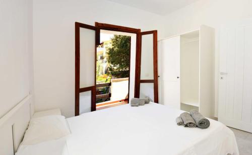 1 dormitorio con cama blanca y espejo en Moderno e ampio trilocale, en Porto Pozzo