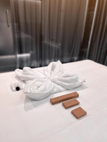 a white towel on a table with two pieces of chocolate at BBC Luxury Apartments in Perintalmanna