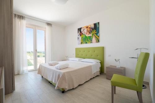 a bedroom with a bed and a green chair at Sul Calar del Sole al Conero in Recanati