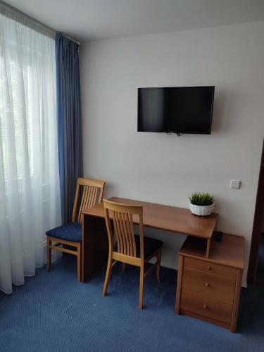 a hotel room with a desk with two chairs and a television at BEST Hotel Garni in Olomouc