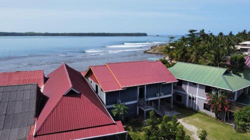 uma vista aérea das casas com telhados vermelhos e do oceano em Yuni Surf House em Lagudri