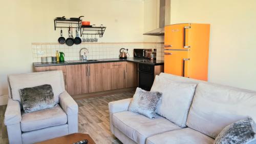 uma sala de estar com um sofá e uma cozinha em St Hilary Central Apartments em Llandudno