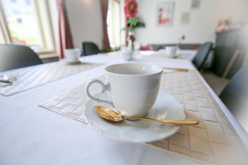 uma chávena de café e uma colher numa mesa em Pension Dáša em Tábor