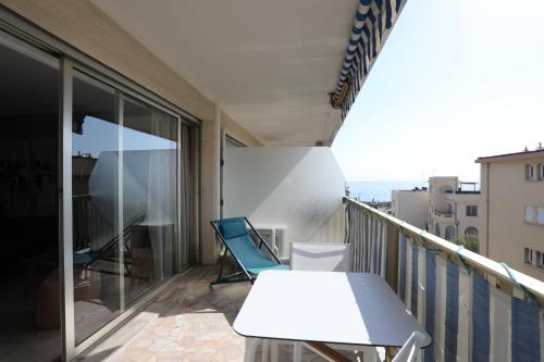 d'un balcon avec une table blanche et une chaise bleue. dans l'établissement Superbe appartement avec terrasse et parking - Antibes - Welkeys, à Antibes