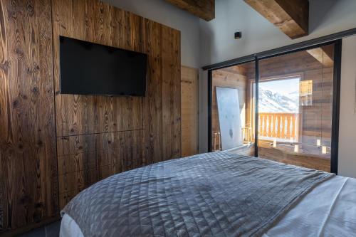 une chambre avec un lit et une télévision sur un mur dans l'établissement SUNWEB Chalets Choseaux Lézami, à Saint-Sorlin-dʼArves