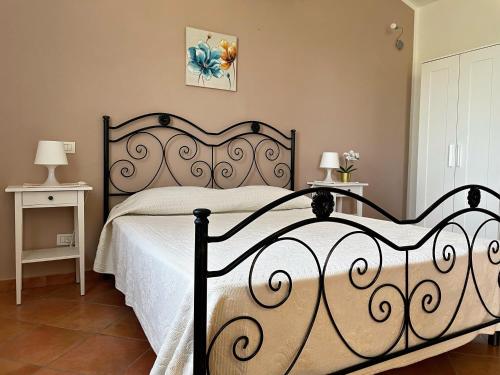 una camera da letto con un grande letto nero con lenzuola bianche di Domus de Goene a Loceri