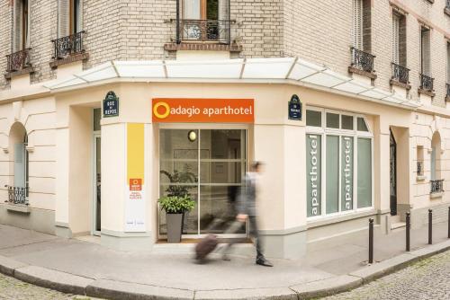 a man walking down a sidewalk in front of a store at Aparthotel Adagio Access Paris Philippe Auguste in Paris