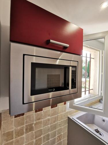 un four à micro-ondes suspendu au-dessus d'un comptoir de cuisine dans l'établissement Maison de vacances L'Hôte Champêtre campagne arlésienne, à Arles