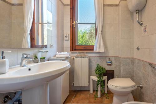 a bathroom with a sink and a toilet and a window at Villa Grazia in Alghero