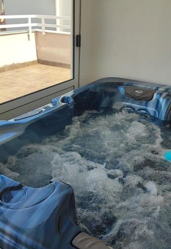a blue tub filled with water next to a window at Spa apartman Iva in Banja Luka