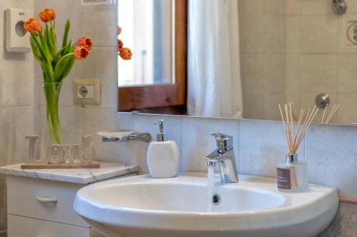 a bathroom with a sink and a vase with orange flowers at Villa Grazia in Alghero