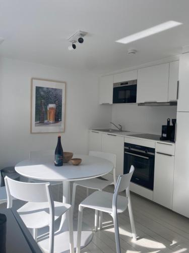 eine weiße Küche mit einem weißen Tisch und Stühlen in der Unterkunft L'atelier de Durbuy in Durbuy