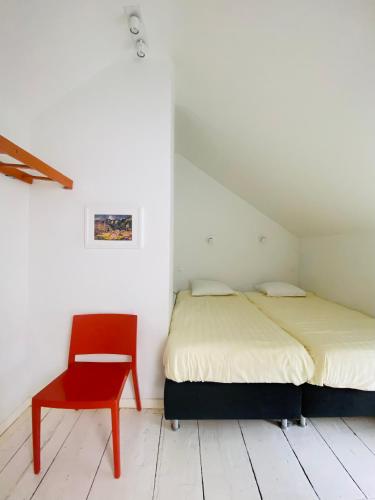 a bedroom with a bed and a red chair at L'atelier de Durbuy in Durbuy