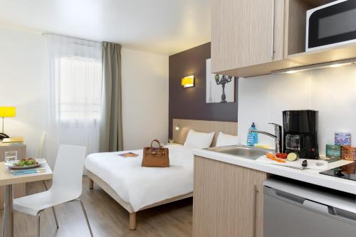 a hotel room with a bed and a kitchen at Aparthotel Adagio Access Paris Clichy in Clichy