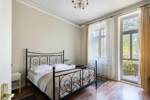 a bedroom with a black bed and windows at Park Apartment (Parkowy) Happy Hours in Sopot