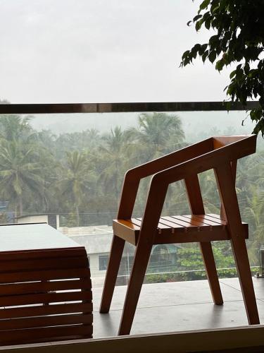 a wooden chair sitting in front of a window at BBC Luxury Apartments in Perintalmanna