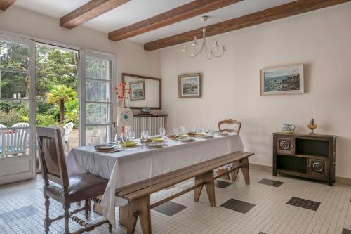 une salle à manger avec une table et des chaises blanches dans l'établissement Maison familiale dans les pins à 300 m de la Plage, à Saint-Brévin-les-Pins