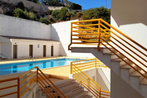 a swimming pool with stairs next to a building at Cerro Apartment in Carvoeiro